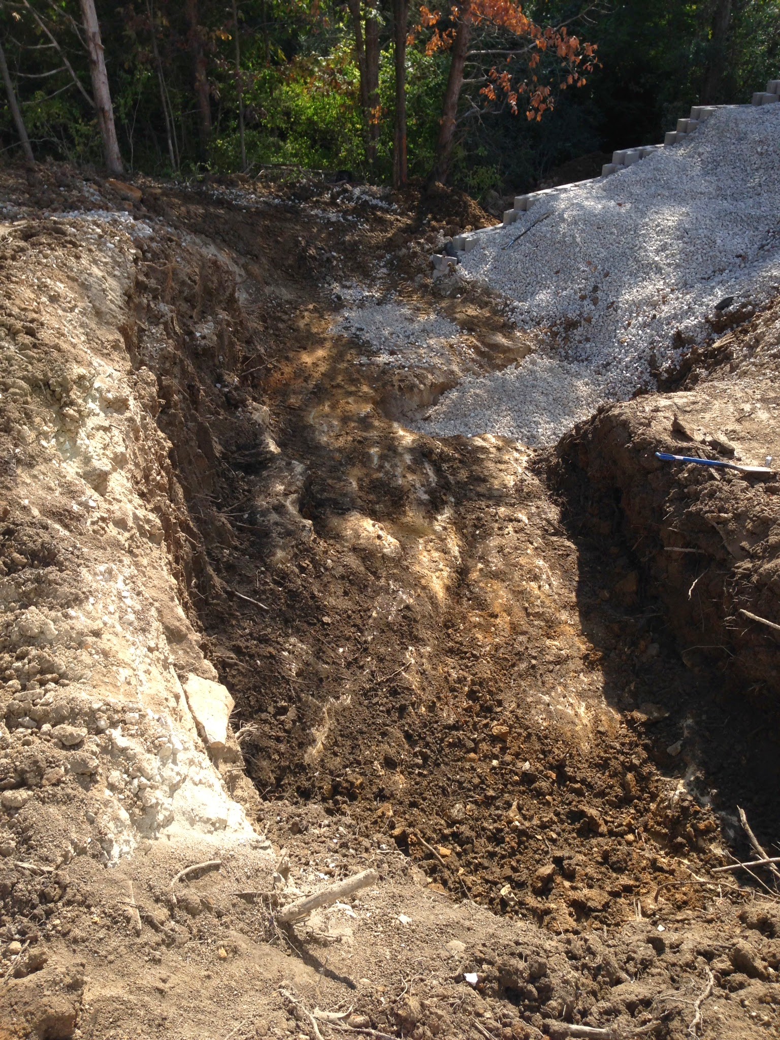 White house by a stream with a view of a forested hill.